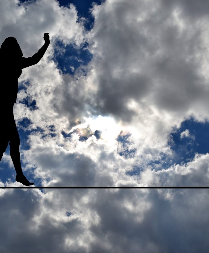 Woman silhouette balancing on rope over blue sky